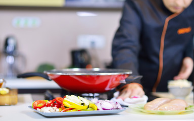 mature chef preparing a meal with various vegetables and meat