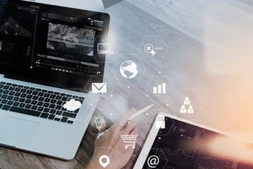 Fototapeta premium businessman working with smart phone and laptop computer on wooden desk in modern office with virtual icons interface