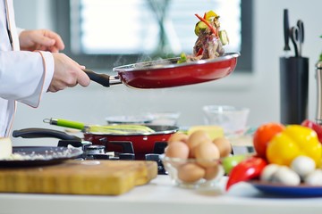 mature chef preparing a meal with various vegetables and meat