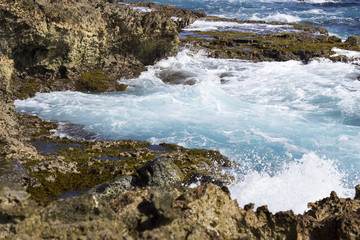 Fototapeta premium The azure waters of the Caribbean Sea crash onto north shore of Aruba, near the collapsed natural bridge and the remaining smaller bridge.