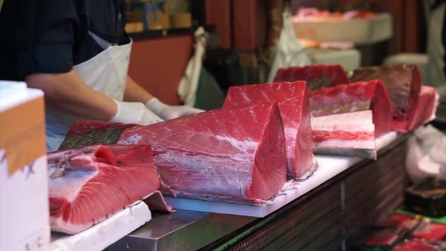 Fresh frozen Japanese maguro whole giant tuna being cut by skilled chefs with sharp knight
