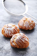 Homemade profiteroles with cream on grey wooden table
