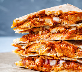 Quesadilla with chicken and cheese. Close-up, dark background.