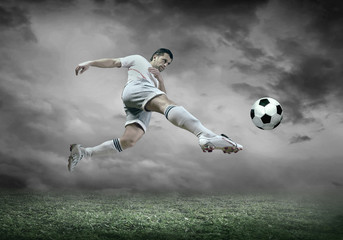 Obraz na płótnie Canvas Football player with ball in action under sky with clouds