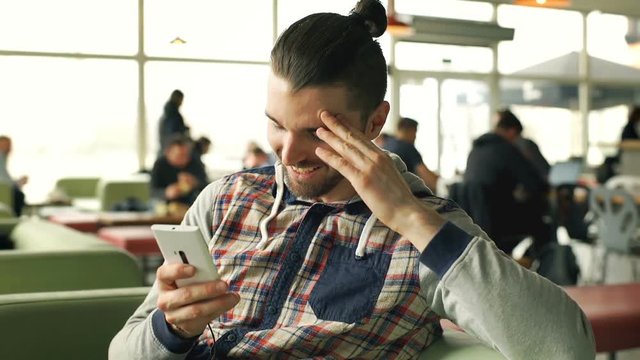 Handsome man receives good news while checking smartphone in the cafe, steadycam shot
