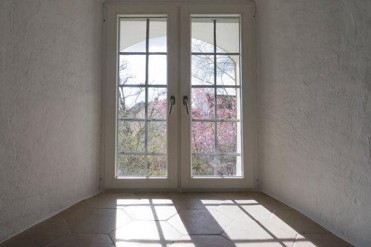 Fenster in Gewölbekeller mit einfallenden Sonnenstrahlen durch die Fensterscheibe