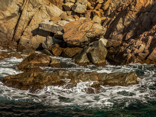 The sea splashing on the rocks.
