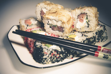 sushi and chopsticks lying on a white plate 