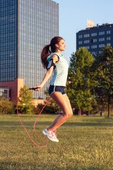 Woman with jumping rope in the city park.