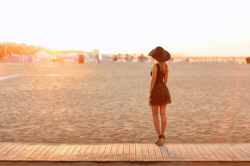 Junge schlanke Frau steht am Strand und schaut auf den Sonnenaufgang