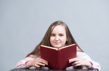 Child girl reading a book of red color