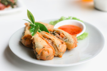 Closeup fried spring rolls served with sweet sauce.