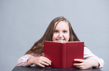 Child girl reading a book of red color