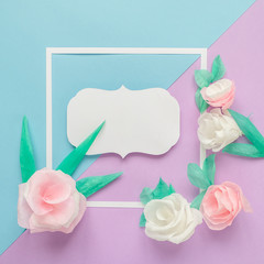 square frame with color paper flowers on the blue and violet background. Flat lay. Nature concept