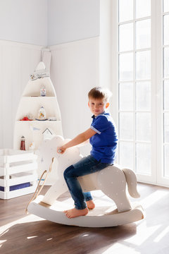 Boy swinging on a rocking horse in the nursery