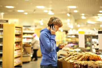 Man shopping in supermarket reading product information. Checking list.
