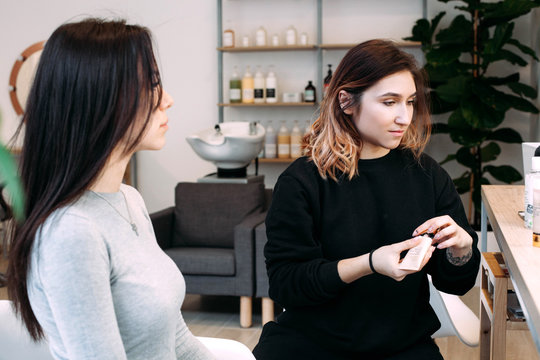 Girl in grey shirt sits before makeup artist