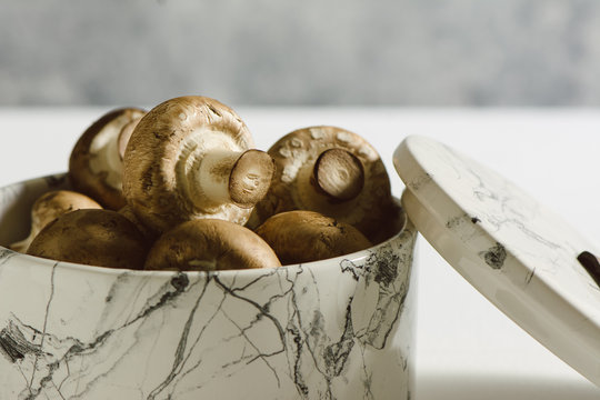 Fresh raw mushrooms, in white marble bowl, portobello variety
