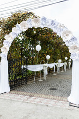 Arch decorated with paper flowers leads to the frontyard