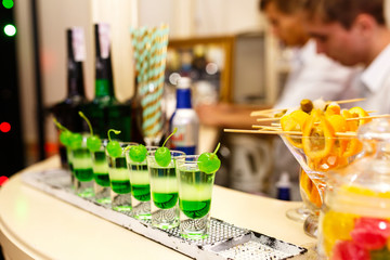 Glasses with green cocktails and green chairs stand on the bar