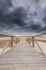 Fototapeta na wymiar wooden fence on dunes and beach at storm weather