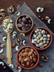 A composition from different varieties of nuts on a wooden background - almonds, cashews, peanuts, walnuts, hazelnuts, pistachios.