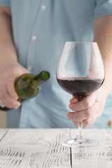 man holding a glass with red wine and bottle