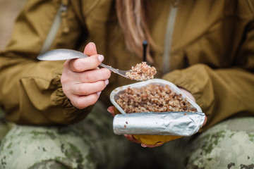 Female hunter preparing food with a portable gas burner in a winter forest.