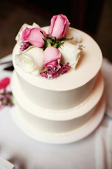 Classy tired wedding cake decorated with pink and white roses on the top