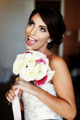 Funny bride with shiny bronze sking has fun posing with wedding bouquet