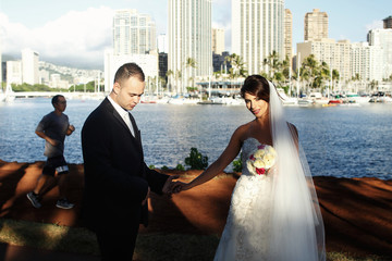 Evening sun makes halo around pretty faces of joyful wedding couple