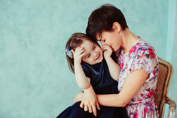The mother with daughter embracing and sitting on the chair