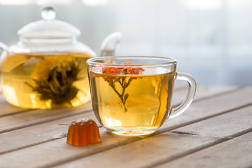 Closeup of cup of tea with bright flower on wooden table with teapot on background. still life with tea cup.