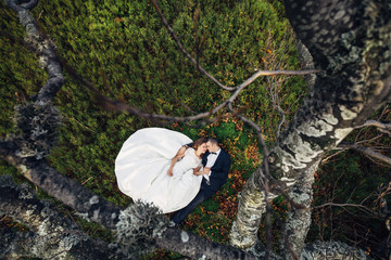 Look from above at dreamy wedding couple lying on autumn ground