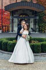 Groom kisses bride's head hugging her from behind tightly