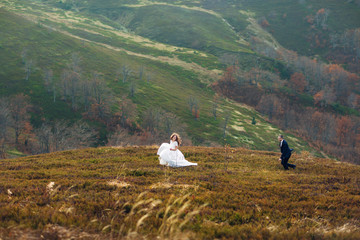 Groom runs to bride while they have fun on autumn hill