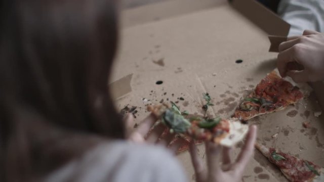 Overhead POV Of Young Couple Eating Takeout Pizza At Home