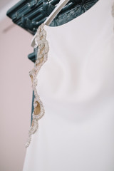 White wedding gown decorated with crystals hangs from the ceiling