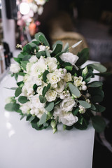 White wedding bouquet with green leaves lies on the table