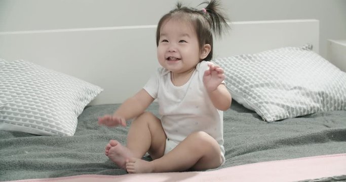 little Asian girl 1 year,having fun on the bed in the room , emotionally expresses joy