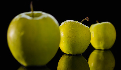 fresh red apple with droplets of water against black background reflection drops