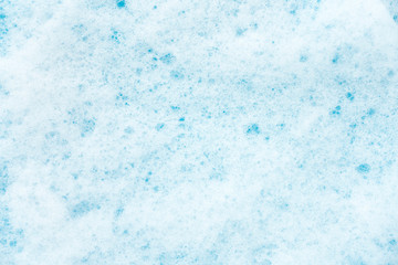 White detergent foam on blue as background.
