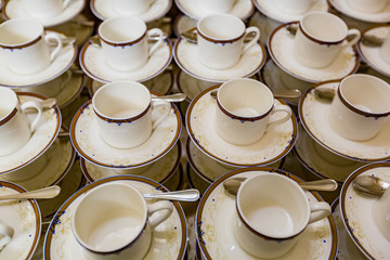 Rows of white porcelain empty cups with saucers for tea and coffee