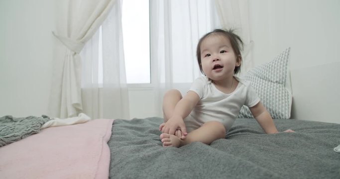 slow motion, little Asian girl 1 year baby ,having fun on the bed in the room , emotionally expresses joy