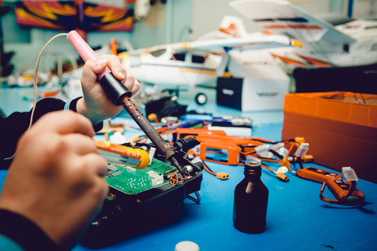 Airplane on the radio control. Repair, soldering iron in the hands of the guy.