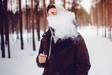 vaping man holding a mod device. cloud of vapor. Vape