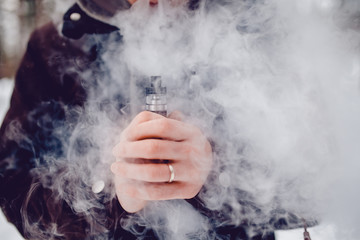 vaping man holding a mod device. cloud of vapor. Vape