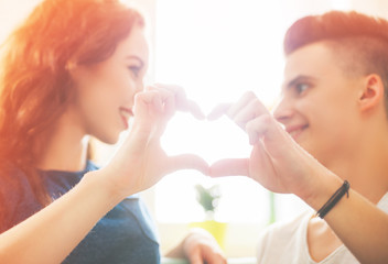 Loving couple at home making heart shape with hands