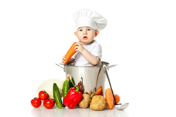 Little boy in chef's hat with ladle, pan and vegetables