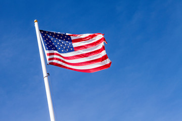 american flag waving in the blue sky, the stars and stripes with white pole